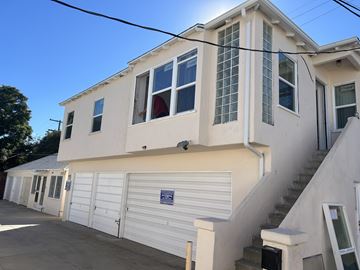 Los Angeles apartment for rent - A white building with a garage door and a staircase leading to the second floor.