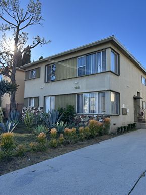 Los Angeles apartment for rent - A beige house with a stone wall and a tree in front.