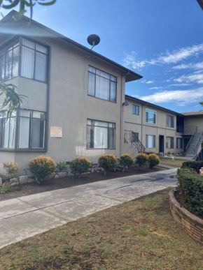 Los Angeles apartment for rent - A building with a sign on the front and bushes in front of it.