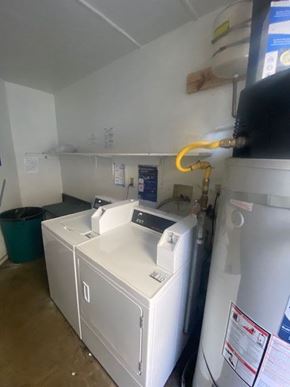 Los Angeles apartment for rent - A yellow hose is hanging from the ceiling in a room with a washing machine and a dryer.
