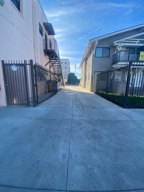 Los Angeles apartment for rent - A long concrete walkway leads between two buildings with black gates on either side.