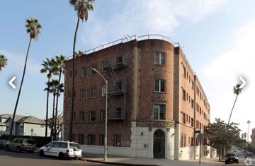 Los Angeles apartment for rent - A red brick building with a white car parked in front.