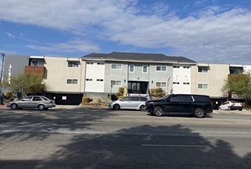 Van Nuys apartment for rent - A black car is parked in front of a white building.
