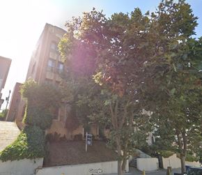 Los Angeles apartment for rent - A tree in front of a building with a sign in front of it.