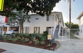 Santa Monica apartment for rent - A house with the number 1232 on it is surrounded by a white fence and has a sign in front of it.