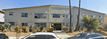 Los Angeles apartment for rent - A building with a white facade and a palm tree in front.
