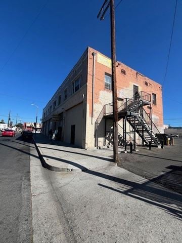 Los Angeles apartment for rent - A red car is parked on the street in front of a brick building with a fire escape.