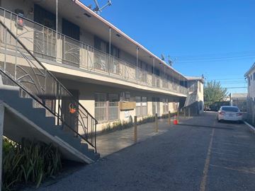Los Angeles apartment for rent - A car is parked on the street in front of a building with a balcony.