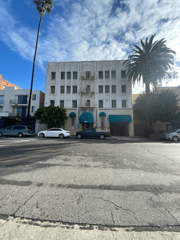 Los Angeles apartment for rent - A white car is parked in front of a building with a blue awning.