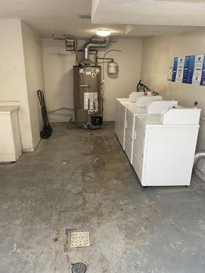 Los Angeles apartment for rent - A dirty utility room with a water heater and a washer and dryer.
