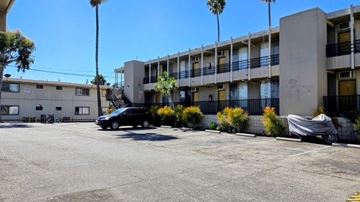 San Pedro apartment for rent - A black car is parked in front of a building with a white car parked in front of a smaller building.