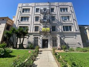 Los Angeles apartment for rent - A grey building with a yellow sign that says "For Sale" in front of it.