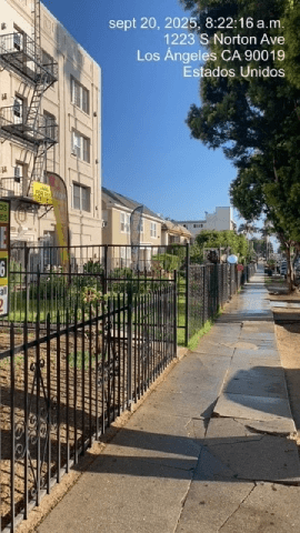 Los Angeles apartment for rent - A black metal fence runs along a sidewalk in front of apartment buildings.