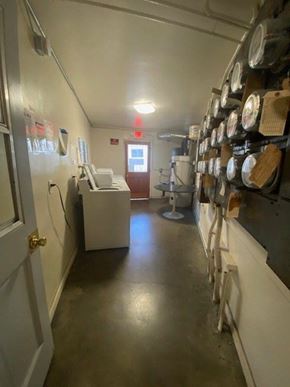 Los Angeles apartment for rent - A long hallway with a white door on the left and a red exit sign above it.