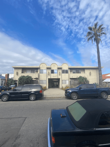 Los Angeles apartment for rent - A black car is parked in front of a building with a palm tree.
