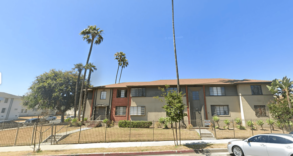 Los Angeles apartment for rent - A white car is parked in front of a two-story building with a red door.