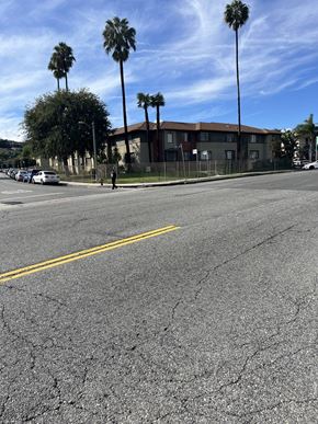 Los Angeles apartment for rent - A street with a yellow line in the middle and palm trees on the side.