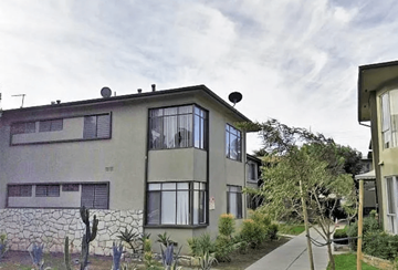Los Angeles apartment for rent - A grey building with a balcony and a wall made of stones.