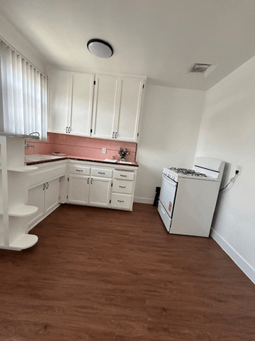 Los Angeles apartment for rent - A kitchen with white cabinets and a pink backsplash.