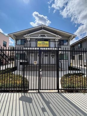 Los Angeles apartment for rent - A house with a sign that says "Now Here Beginning" is behind a black fence.