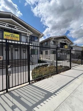 Los Angeles apartment for rent - A fence surrounds a building with a sign that says "NOW RENTING".
