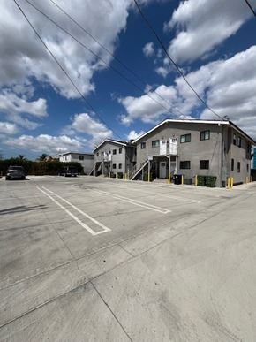 Los Angeles apartment for rent - A large grey building with a parking lot in front.