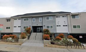 Van Nuys apartment for rent - A modern building with a grey and white facade and a black roof.