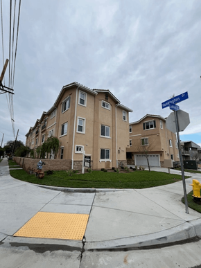 San Gabriel apartment for rent - A building with a brown facade and a yellow sign on the sidewalk.