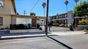 San Pedro apartment for rent - A street view of a residential area with a house and apartment buildings.