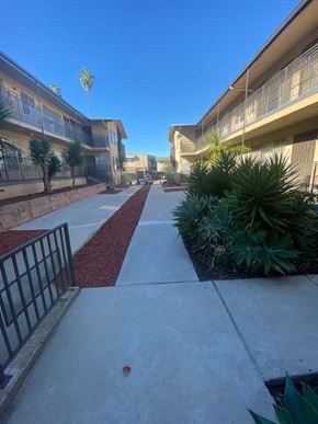 Los Angeles apartment for rent - A red brick pathway leads to a building with a black gate on the left.