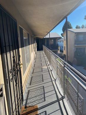 Los Angeles apartment for rent - A long balcony with a metal railing and a brown rug on the floor.