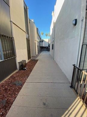 Los Angeles apartment for rent - A narrow alley with a sidewalk and a metal railing.