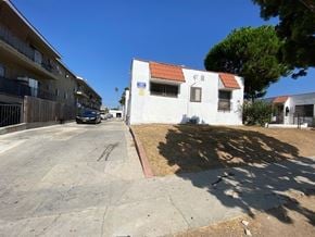 Los Angeles apartment for rent - A white house with a red roof is situated in a parking lot.
