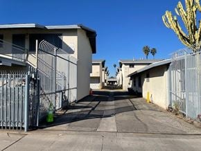 Compton apartment for rent - A long driveway with a metal fence and a cactus in the background.