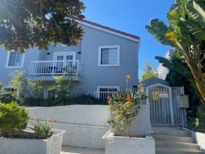 Santa Monica apartment for rent - A house with a grey facade and a red roof is surrounded by greenery.