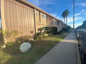 Gardena apartment for rent - A building with a brown facade and a large rock in the front yard.
