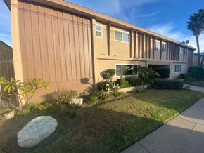 Gardena apartment for rent - A building with a brown facade and a large rock in the front yard.