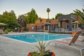 Fair Oaks apartment for rent - A pool surrounded by chairs and plants with a building in the background at Fountains of Fair Oaks, Fair Oaks