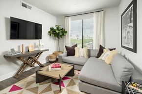 Phoenix apartment for rent - A living room with a grey couch, a coffee table, and a flat screen TV mounted on the wall.