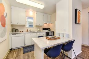 Davis apartment for rent - a kitchen with white cabinets and a white table with blue chairs at Renaissance Park Apartments, California, 95618