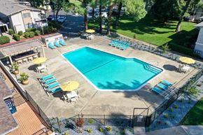 Davis apartment for rent - Drone photo of the community swimming pool area which is fenced and pool deck is filled with seating options. at Renaissance Park Apartments, Davis, CA, 95618
