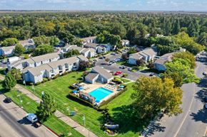 Davis apartment for rent - Drone photo overlooking the entire apartment community showcasing the pool, leasing office, mature landscaping and all of the apartment buildings. at Silverstone Apartments, Davis, California