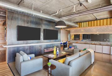 Longmont apartment for rent - A modern living room with a grey couch and a television mounted on the wall.