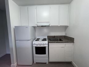 Canoga Park apartment for rent - A small kitchen with a white fridge, stove, and cabinets.