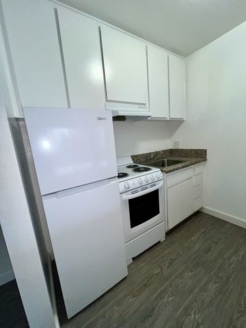 Canoga Park apartment for rent - A white fridge and stove in a kitchen with white cabinets.