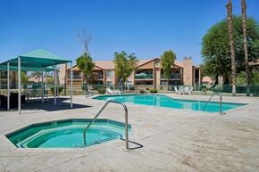 Palm Desert apartment for rent - A swimming pool area with a green canopy and a building in the background.