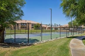 Palm Desert apartment for rent - A tennis court surrounded by a fence and trees.