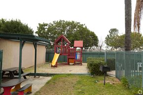 Vista apartment for rent - A playground with a red slide and a red and white playhouse.