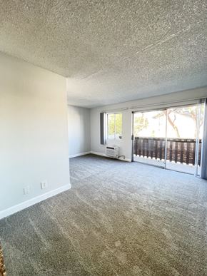 Canoga Park apartment for rent - A room with a carpeted floor and a sliding glass door leading to a balcony.