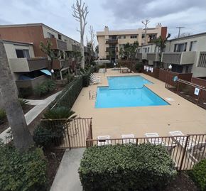 Canoga Park apartment for rent - A pool surrounded by apartment buildings and greenery.